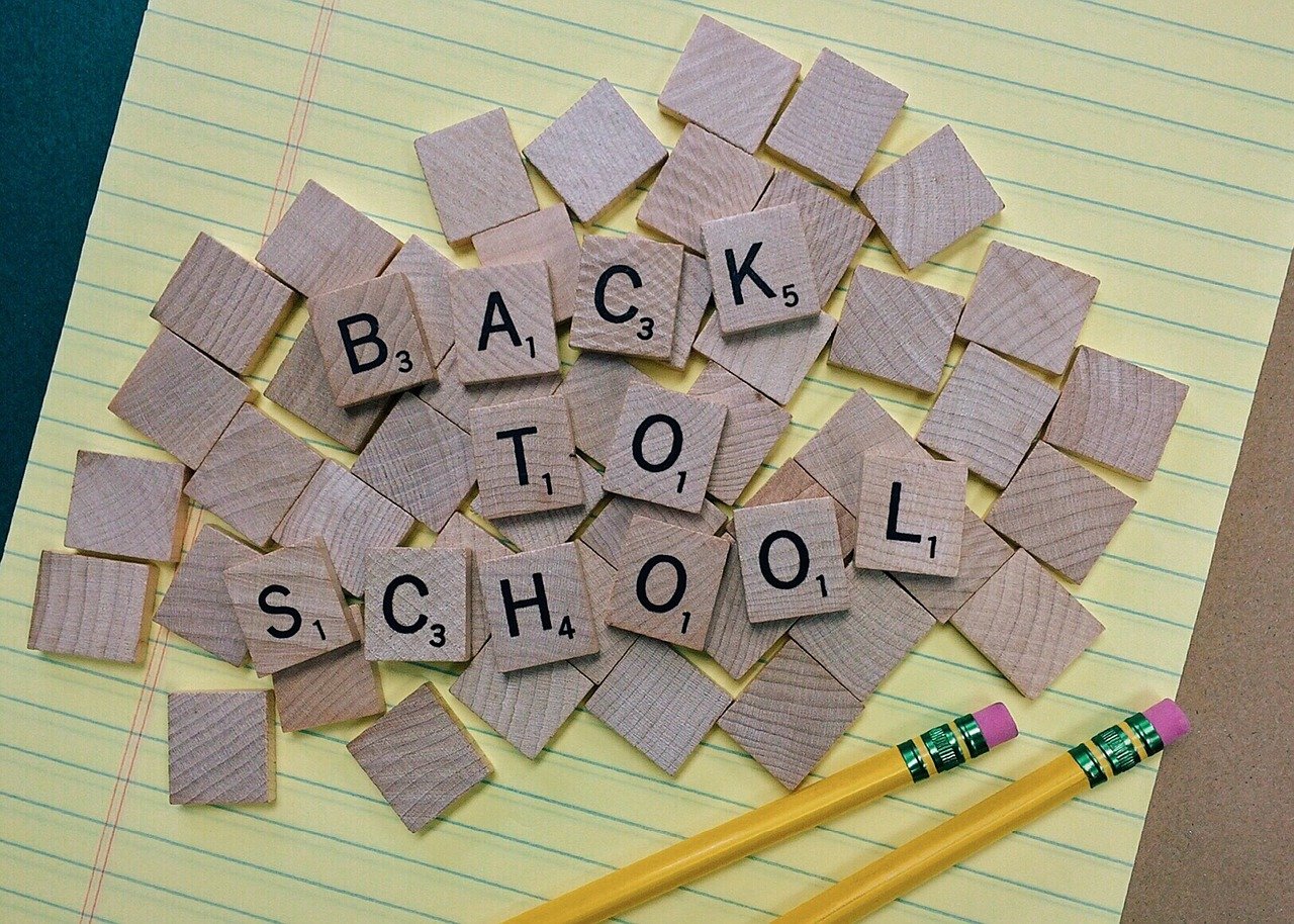 Back to School written in scrabble letter pieces. Yellow lined notebook and pencils. Source: Pixabay.