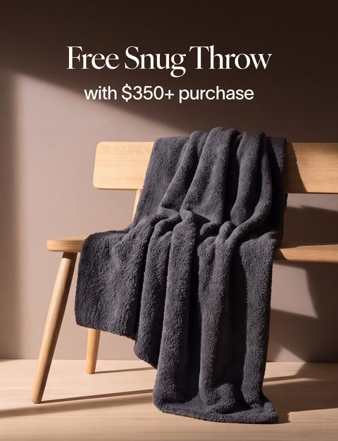 Charcoal gray Snug Throw draped over a light wood bench. Free Snug Throw with $350+ purchase.