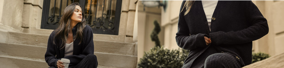 A woman wearing a dark navy blue cardigan sweater with gold buttons, shown in a lifestyle setting on outdoor stone steps.