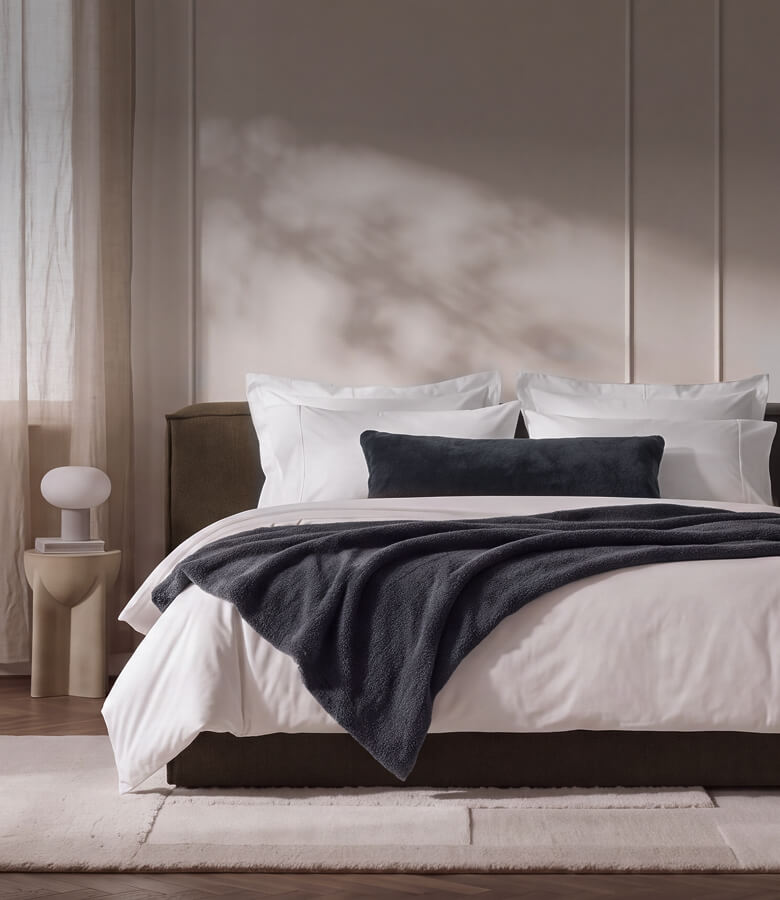 Charcoal gray Snug Throw draped over a light wood bench. Free Snug Throw with $350+ purchase.