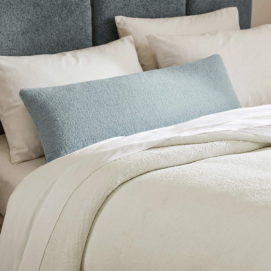 Sunday Citizen Snug Lumbar Pillow in Misty Blue on a bed 