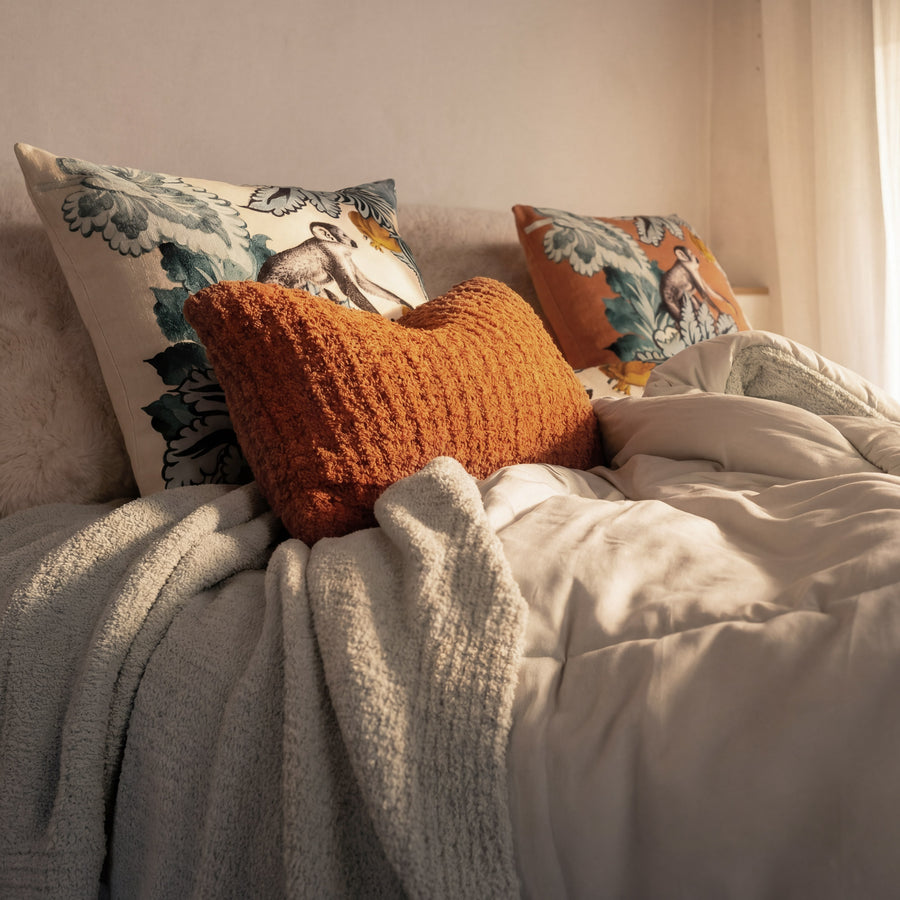 Sunday Citizen Demasc Monkey Throw Pillow in Slate Grey and Koi styled on a modern bed